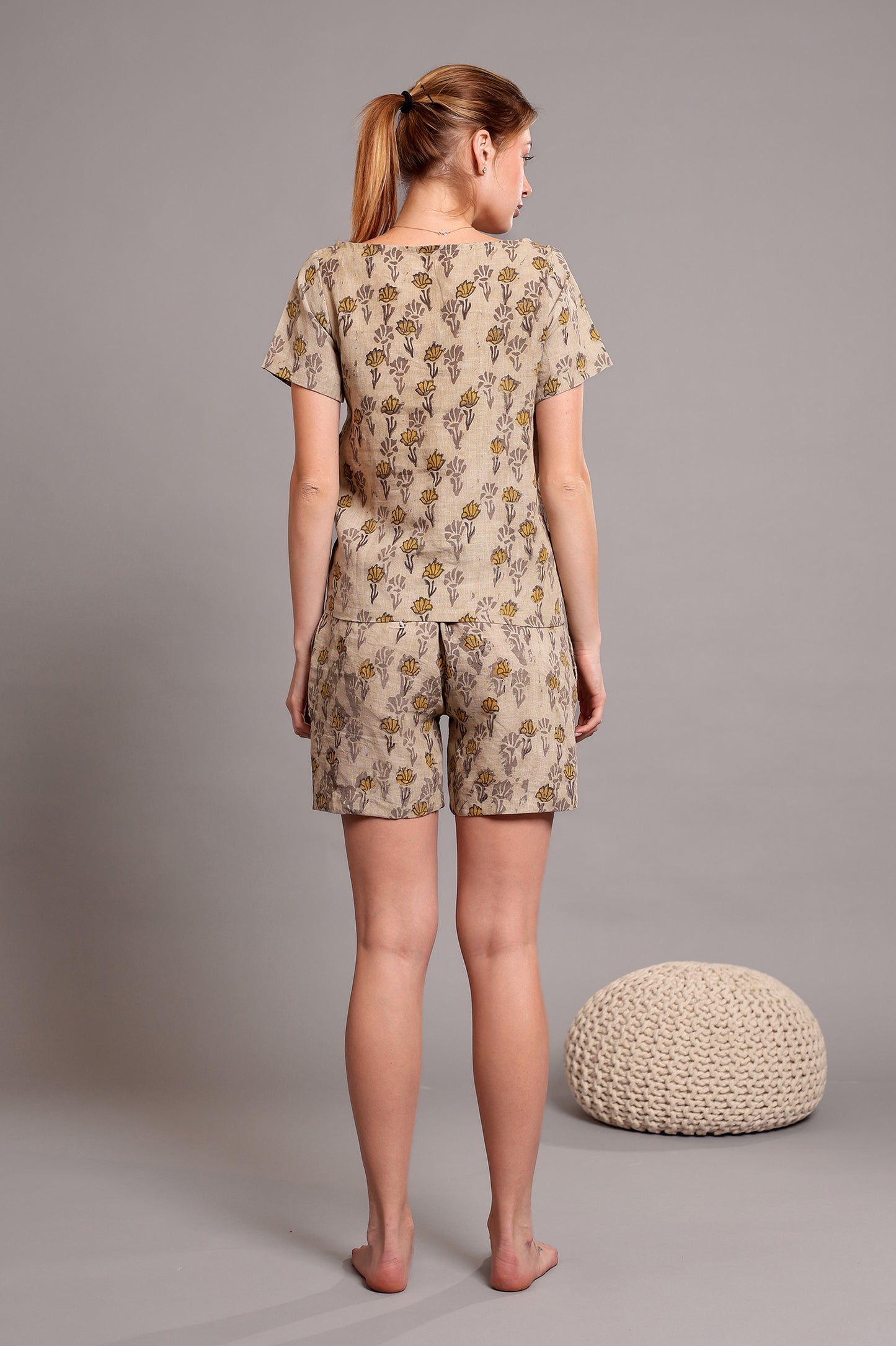 Woman wearing a linen floral top and shorts pajama set against a gray background.