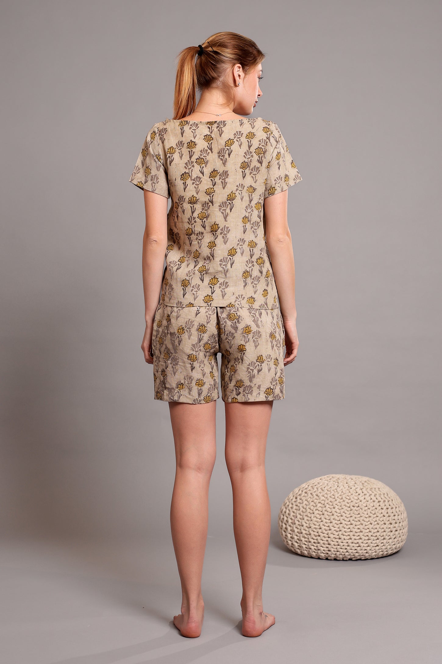 Woman wearing a linen floral top and shorts pajama set against a gray background.