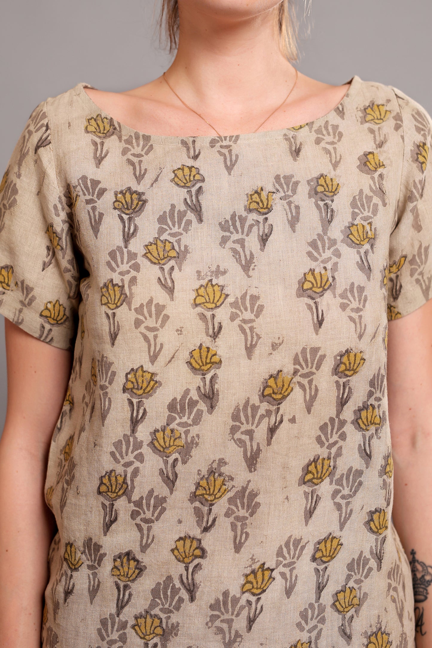 Person wearing a beige linen floral top against a neutral background.