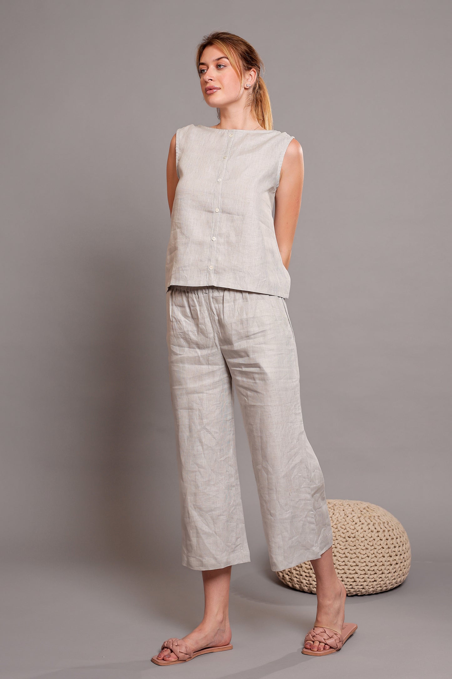 Woman wearing a light gray linen sleeveless top paired with linen pants against a gray background.