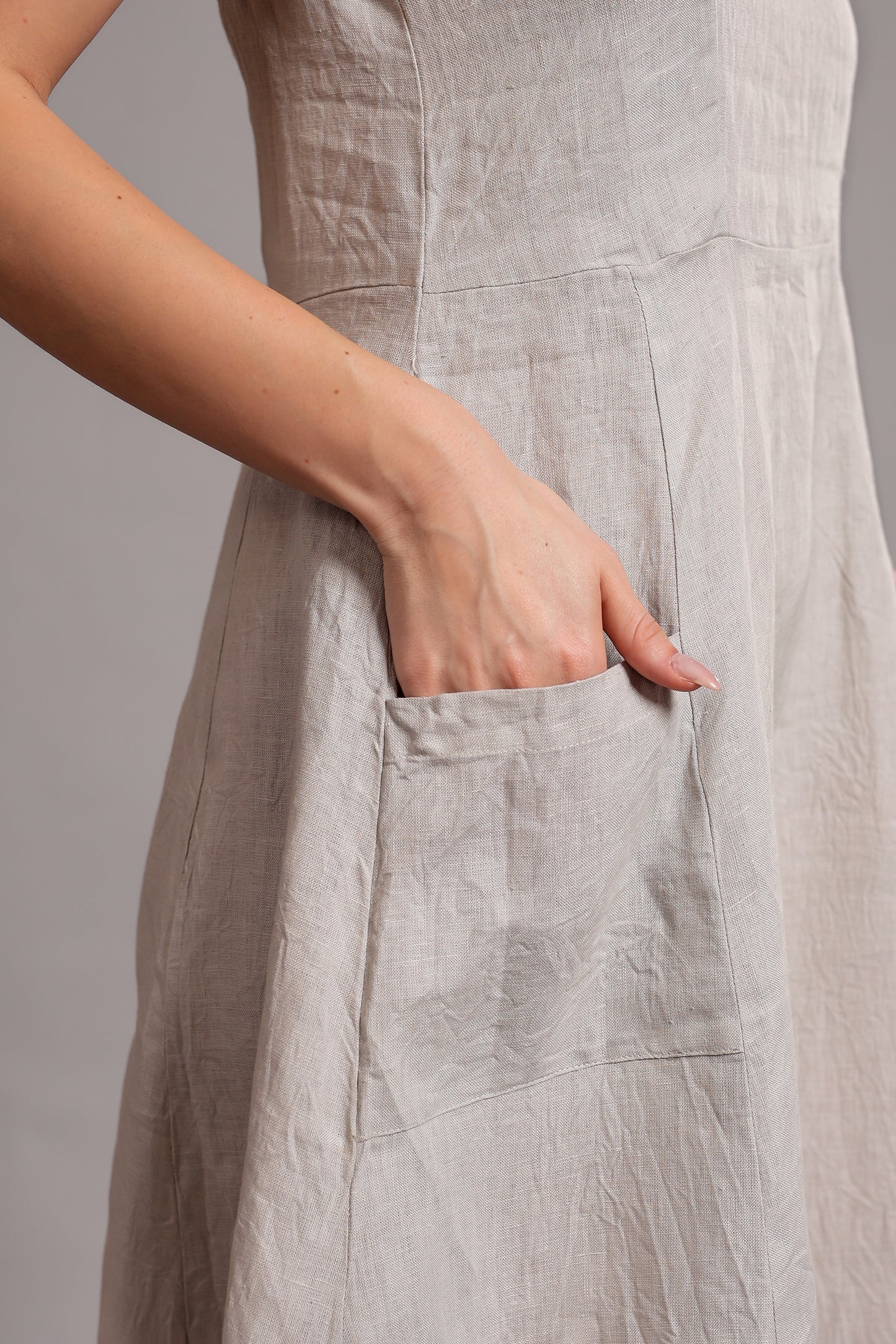 Person wearing a light gray linen midi dress with a pocket against a plain background.