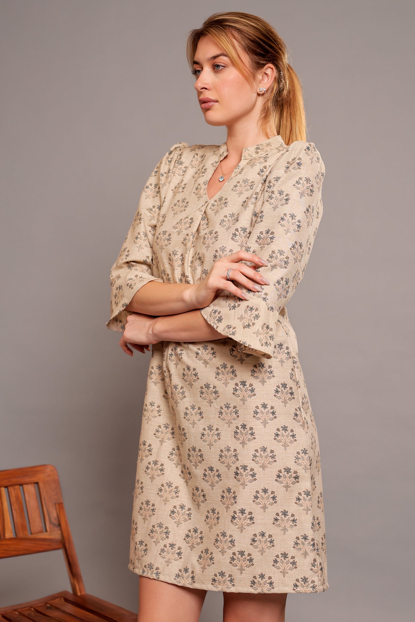 Woman wearing a linen floral dress against a gray background.