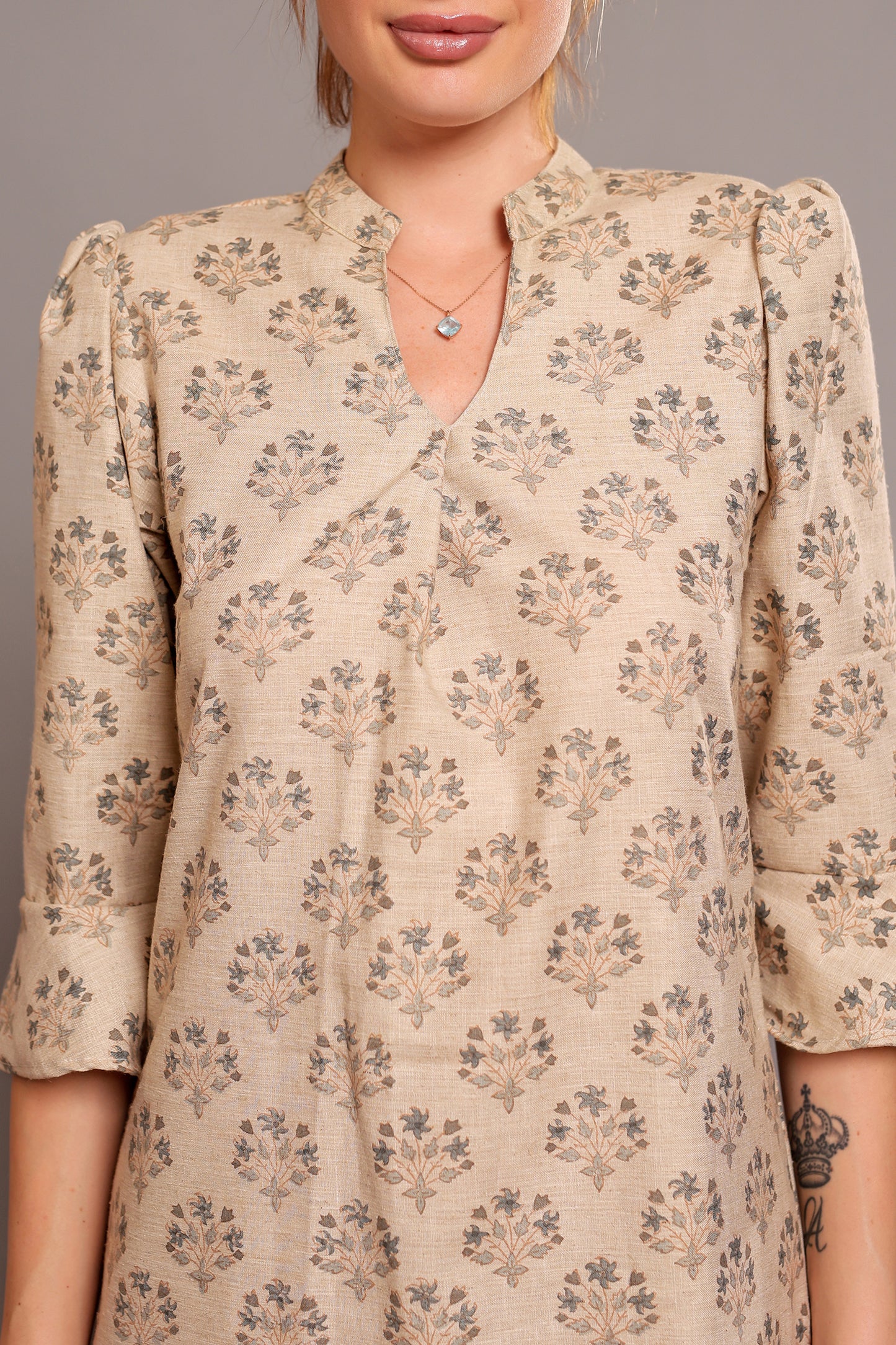 Model wearing a beige linen floral dress against a neutral background.