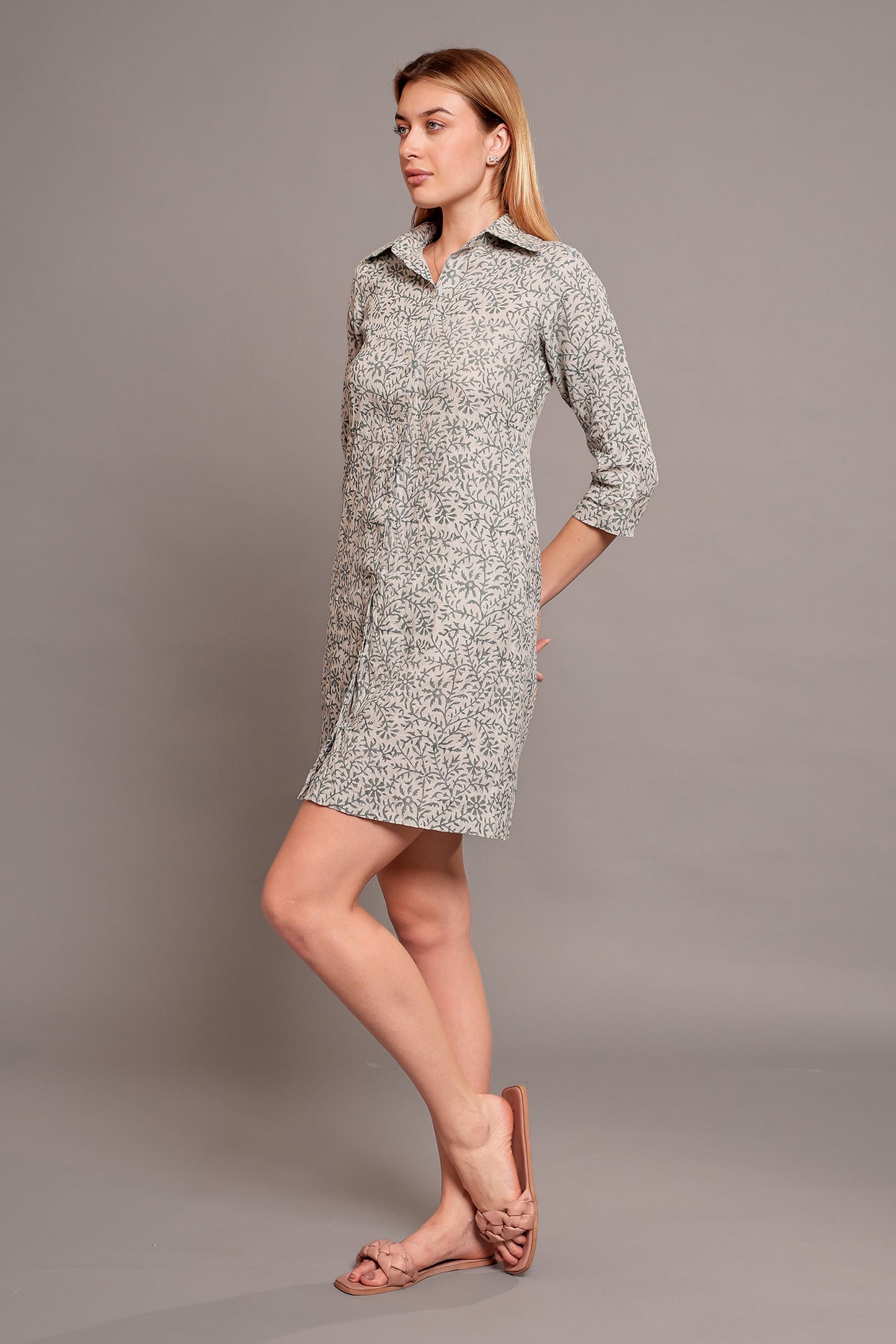 Woman wearing a patterned linen short dress against a gray background.