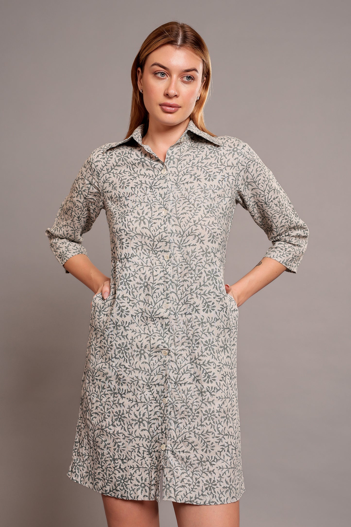 Woman wearing a patterned linen floral dress against a gray background.