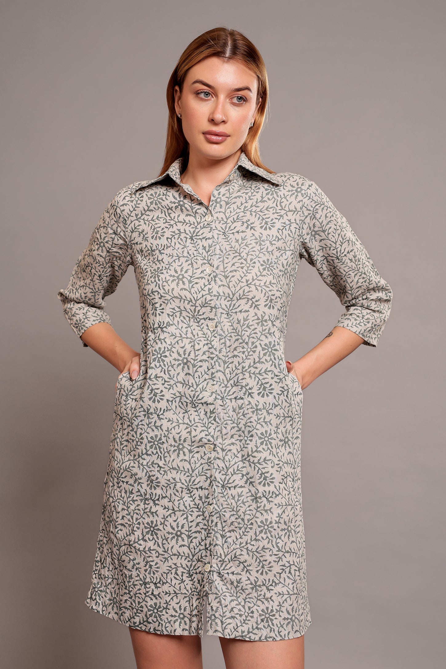 Woman wearing a patterned linen floral dress against a gray background.