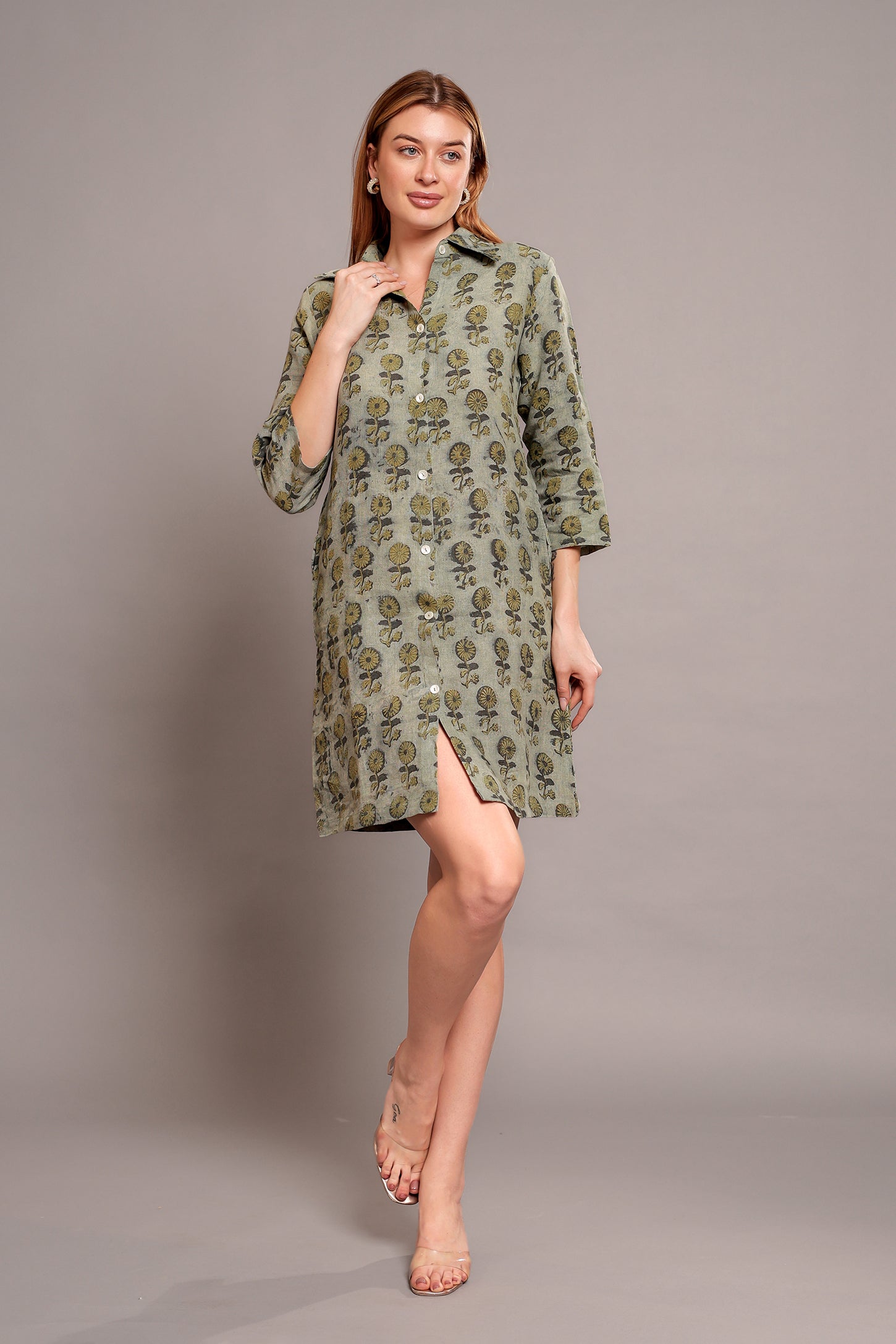Woman wearing a green patterned linen mini dress on a gray background.