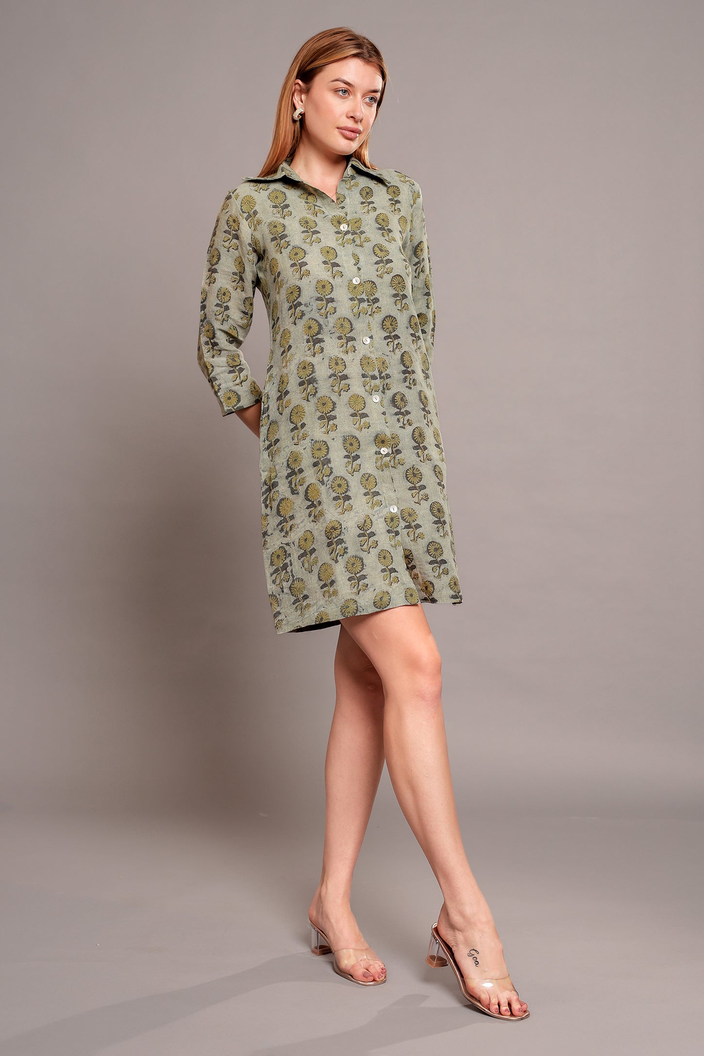 Woman wearing a green patterned linen mini dress against a gray background.