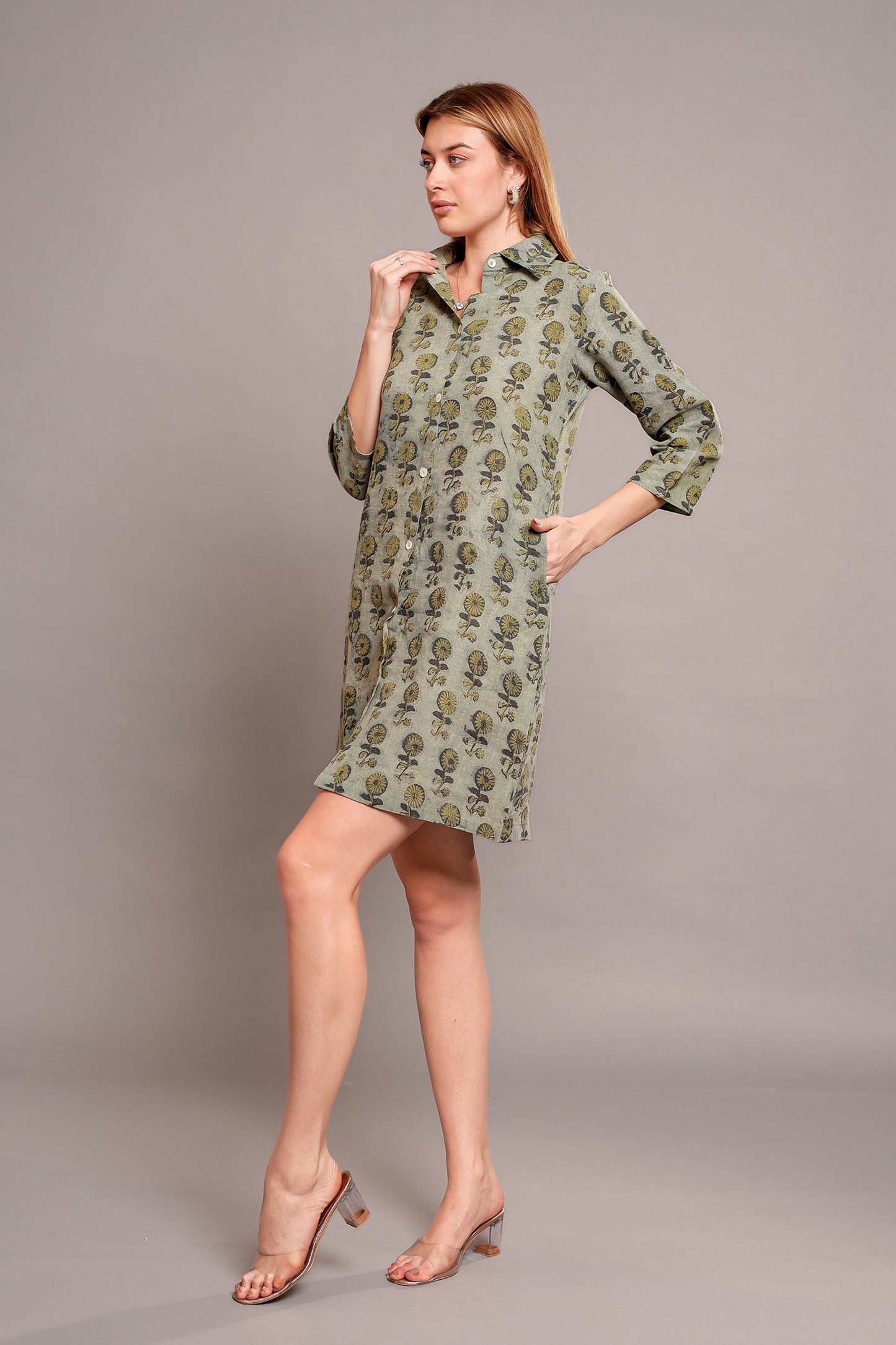 Woman wearing a green floral linen mini dress against a gray background.