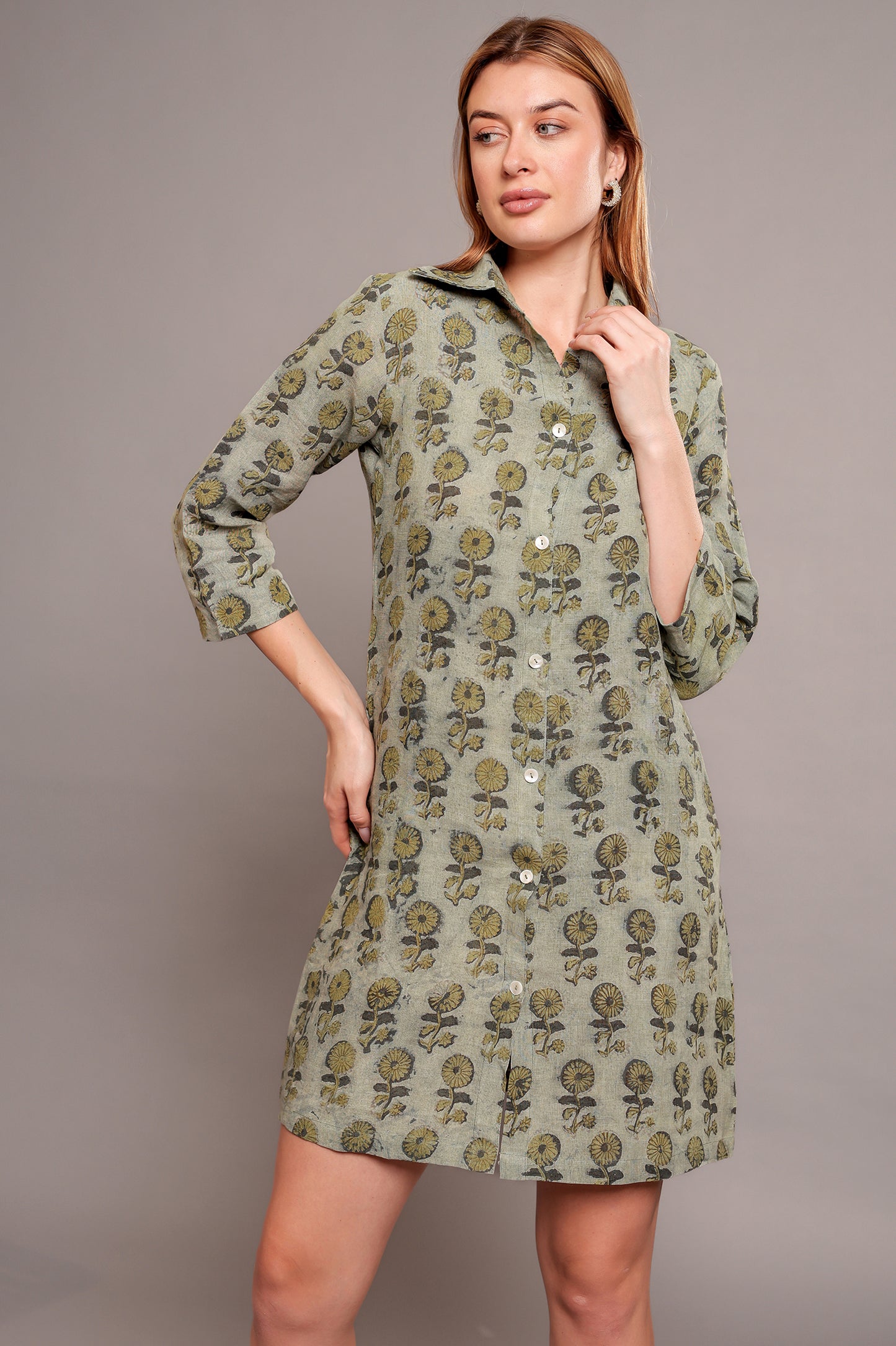 Woman wearing a green floral linen mini dress against a gray background.