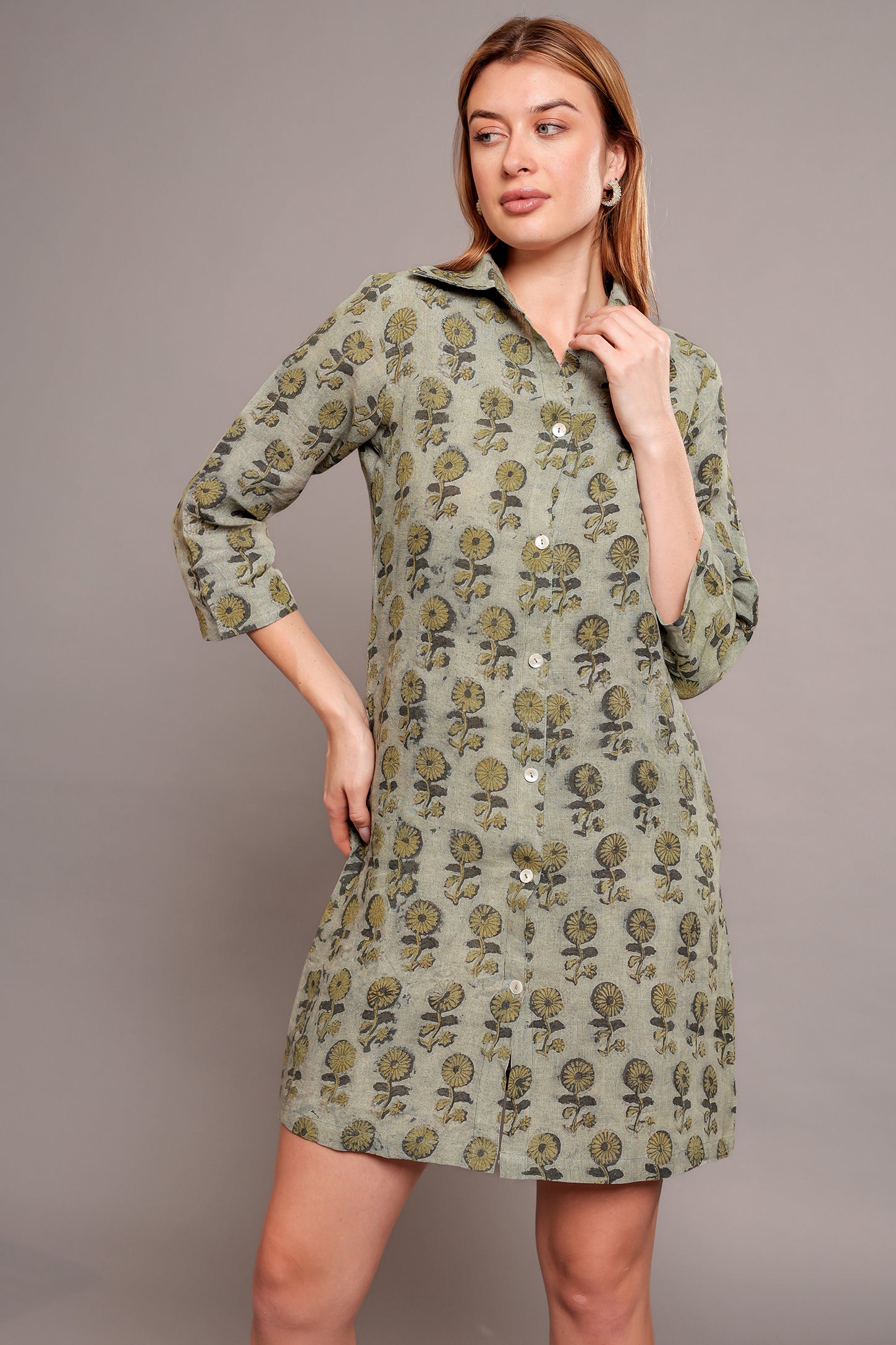 Woman wearing a green floral linen mini dress against a gray background.