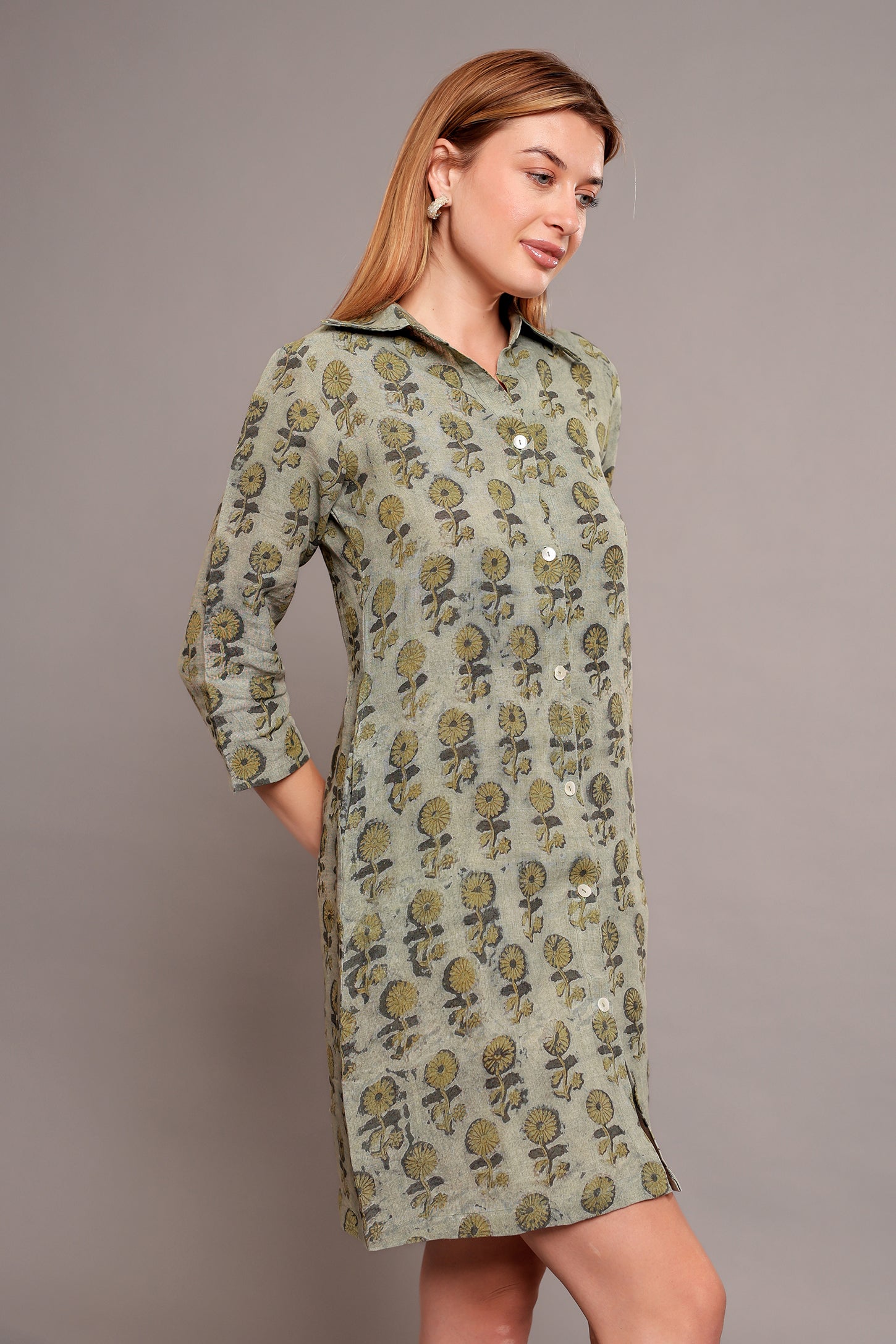Woman wearing a green floral linen mini dress against a gray background.